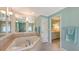 This bathroom offers a tiled tub and a large mirror with views into another room at 7604 Weeping Willow Cir, Sarasota, FL 34241