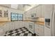 Well-lit kitchen with white cabinets, granite countertops, and a black and white checkered floor at 7604 Weeping Willow Cir, Sarasota, FL 34241