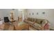 Living room features a floral sofa, wood floors, and a view of the front entrance and office at 7604 Weeping Willow Cir, Sarasota, FL 34241