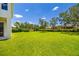 Expansive backyard featuring lush green grass, mature trees, and meticulous landscaping at 7727 Heyward Cir, University Park, FL 34201