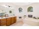 Bathroom featuring a large tub, arched windows, and wood vanities at 7727 Heyward Cir, University Park, FL 34201