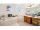 Bathroom featuring a large tub, arched windows, and wood vanity at 7727 Heyward Cir, University Park, FL 34201