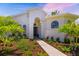 Home entrance with a beautifully landscaped front yard, walkway, and arched windows at 7727 Heyward Cir, University Park, FL 34201
