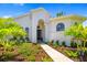 Home entrance with a beautifully landscaped front yard, walkway, and arched windows at 7727 Heyward Cir, University Park, FL 34201