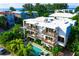 Aerial view of a modern white building with balconies and a refreshing pool surrounded by tropical foliage at 804 N Shore Dr, Anna Maria, FL 34216