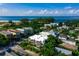 An aerial view of a white home in tropical landscaping, showcasing a pool with beach views and blue skies at 804 N Shore Dr, Anna Maria, FL 34216
