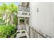 Multi-level balcony exterior featuring white walls, glass railings, and tropical foliage at 804 N Shore Dr, Anna Maria, FL 34216
