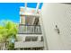 Multi-level balcony exterior featuring white walls, glass railings, and tropical foliage at 804 N Shore Dr, Anna Maria, FL 34216
