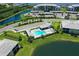 Aerial view of community pool and amenity center surrounded by lush landscaping and parking at 850 Tidewater Shores Loop # 102, Bradenton, FL 34208