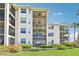 Multi-story condo building featuring screened balconies, manicured lawn, and lush landscaping at 850 Tidewater Shores Loop # 102, Bradenton, FL 34208
