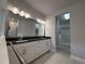 Bathroom with dual vanity, sleek black countertop, bright lighting, and walk-in closet access at 8706 Arrow Creek Dr, Parrish, FL 34219