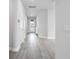 A bright hallway with wood-look floors leads to the front door, showcasing the home's modern design at 8706 Arrow Creek Dr, Parrish, FL 34219