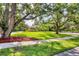 Well-manicured front yard with mature trees and lush green grass leading to a charming home at 8717 Misty Creek Dr, Sarasota, FL 34241