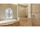 Luxurious bathroom with a soaking tub under a decorative window and a frameless glass shower at 8832 Enclave Ct, Sarasota, FL 34238