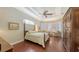 Comfortable bedroom with hardwood floors, tray ceiling, and sitting area with a view at 8832 Enclave Ct, Sarasota, FL 34238