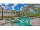 Tranquil screened pool area with spa, offering a private retreat with lush landscaping and clear blue skies at 8832 Enclave Ct, Sarasota, FL 34238