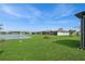 Expansive backyard with lush green lawn, leading to a tranquil pond under a partly cloudy blue sky at 9566 Coastline Way, Parrish, FL 34219