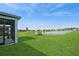 Picturesque view from a screened lanai overlooking a vast green lawn and a serene pond, under a bright sky at 9566 Coastline Way, Parrish, FL 34219