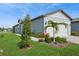 Charming single-story home with lush landscaping, including palm trees and flowering shrubs, leading to the garage at 9566 Coastline Way, Parrish, FL 34219