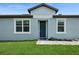 Inviting front entrance with a navy door framed by white trim, flanked by symmetrical windows and lush grass at 9566 Coastline Way, Parrish, FL 34219