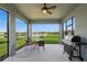 Outdoor screened patio with ceiling fan and dining area overlooking lake, with grill at 9566 Coastline Way, Parrish, FL 34219