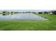 Scenic view of a calm pond, reflecting the blue sky, surrounded by a neatly manicured green lawn at 9566 Coastline Way, Parrish, FL 34219