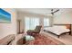 Bright bedroom with light wood flooring, accent rug, chaise lounge, and a decorative ceiling fan at 1076 Toc0Baga, Sarasota, FL 34234