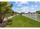 Grassy backyard features white picket fence with beautiful landscaping with trees and palms at 11839 Shrewsbury Ln, Parrish, FL 34219