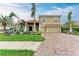 Attractive two-story home boasts a brick driveway, manicured lawn, and tropical landscaping at 12814 Daisy Pl, Bradenton, FL 34212