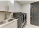 Modern laundry room featuring a sink, white cabinets, and stacked washer and dryer units at 12814 Daisy Pl, Bradenton, FL 34212