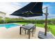 Outdoor dining area under a large umbrella next to a pool and green lawn at 12814 Daisy Pl, Bradenton, FL 34212