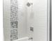 Close up of a shower with white wave pattern tile and decorative mosaic tile accent at 12814 Daisy Pl, Bradenton, FL 34212