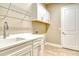 The laundry room features a utility sink, bright cabinets and drawers, and modern wood-look floors at 13908 Painted Loop, Parrish, FL 34219