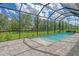Relaxing pool area featuring a screened enclosure, stone paver patio, and lush landscaping at 13908 Painted Loop, Parrish, FL 34219