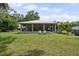 Exterior view of the house featuring a screened-in porch, grill, and expansive lawn at 15780 Wilson Rd, Sarasota, FL 34240