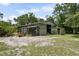 Exterior view of a large barn with open doors and stalls, surrounded by natural landscape at 15780 Wilson Rd, Sarasota, FL 34240