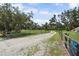 Gravel driveway with wooden fence, leading to a home with mature trees at 15780 Wilson Rd, Sarasota, FL 34240