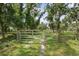 Gated entry on a long driveway through mature trees offering privacy and security to the property at 15780 Wilson Rd, Sarasota, FL 34240