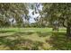 Picturesque view of a wide-open green field with mature trees and a vintage tractor on the land at 15780 Wilson Rd, Sarasota, FL 34240