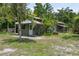 Exterior view of a rustic outbuilding with a weathered door, overgrown foliage, and vintage charm at 15780 Wilson Rd, Sarasota, FL 34240