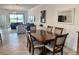 Open-concept dining room with elegant wooden table, view of living room and sliding glass doors to the backyard at 16087 Sunny Day Dr, Bradenton, FL 34211