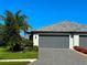 Exterior view of a well-kept home featuring a grey two car garage, pavers, manicured lawn, and vibrant landscaping at 16087 Sunny Day Dr, Bradenton, FL 34211