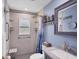 Bright bathroom with a shower featuring grab bars, a seat, and a window, plus a gray vanity with sink at 1778 N Salford Blvd, North Port, FL 34286