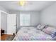 Well-lit bedroom features a quilt, throw pillows, wood flooring and a white door and window at 1778 N Salford Blvd, North Port, FL 34286