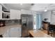 Modern kitchen with stainless steel refrigerator, white cabinets, and an adjacent dining area with outdoor access at 1778 N Salford Blvd, North Port, FL 34286
