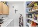 Functional laundry room with washer, dryer, storage shelves, and an ironing board for added convenience at 1778 N Salford Blvd, North Port, FL 34286