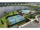Aerial view of community amenities including a pool, clubhouse, and tennis courts near a lake, offering a luxury lifestyle at 18039 Cherished Loop, Bradenton, FL 34211