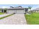 Paired villas feature a brick paver driveway, attached two-car garage, and neatly landscaped yard at 18039 Cherished Loop, Bradenton, FL 34211
