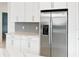 Modern kitchen with stainless steel refrigerator, white cabinets, and gray tile backsplash at 18039 Cherished Loop, Bradenton, FL 34211