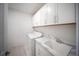A well-lit laundry room with white cabinets, countertop space, utility sink, and modern appliances at 18039 Cherished Loop, Bradenton, FL 34211